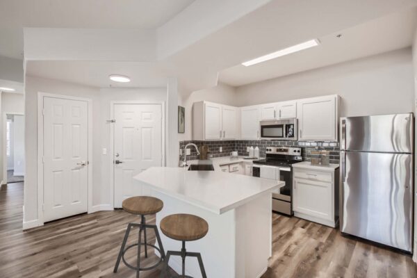 Villas at Mountain Vista Ranch apartment kitchen with wood style floor, white cabinets and counters, and stainless steel appliances.
