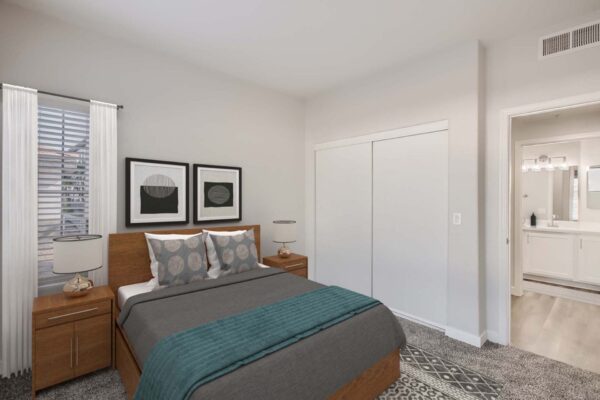 Villas at Mountain Vista Ranch apartment bedroom with carpet, plush bed with headboard, bedside tables with lamps, and large window.