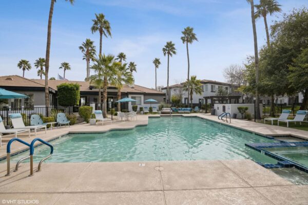 Villas at Mountain Vista Ranch apartments pool area with lounge chairs and umbrellas.