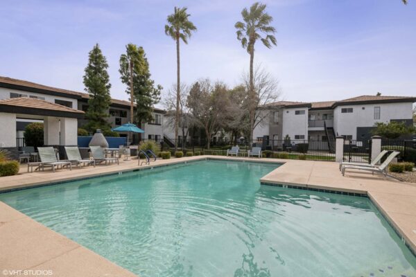 Villas at Mountain Vista Ranch apartments pool area with lounge chairs and tall palm trees.