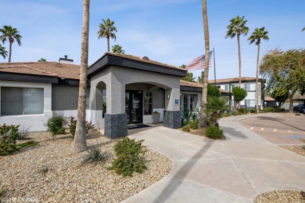 Villas at Mountain Vista Ranch apartments entrance with ample parking and tall palm trees.