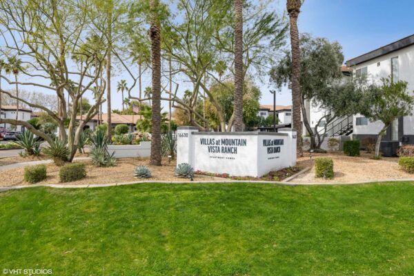 Villas at Mountain Vista Ranch apartments monument sign with lush landscaping and tall palm trees.