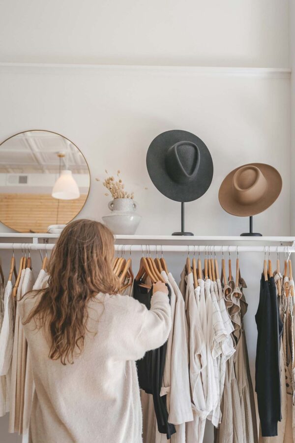 Person shopping at boutique with chic clothes and hats.