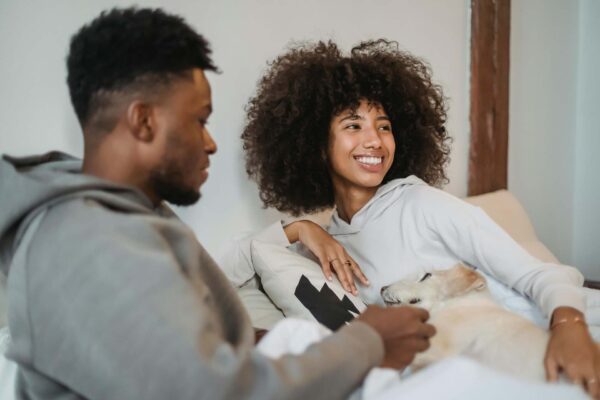 A couple with their dog sitting on a couch at home.