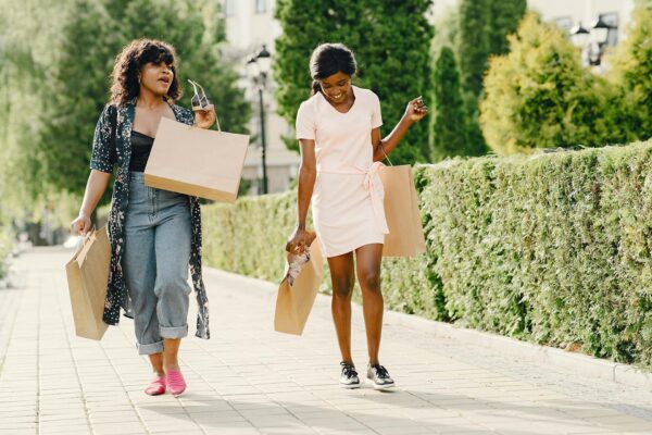 Two friends laughing and walking together with shopping bags.