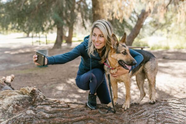 Person taking selfie with their german shepherd dog at rugged park.