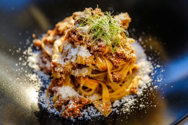 Bowl of pasta with meat sauce and parmesan cheese.