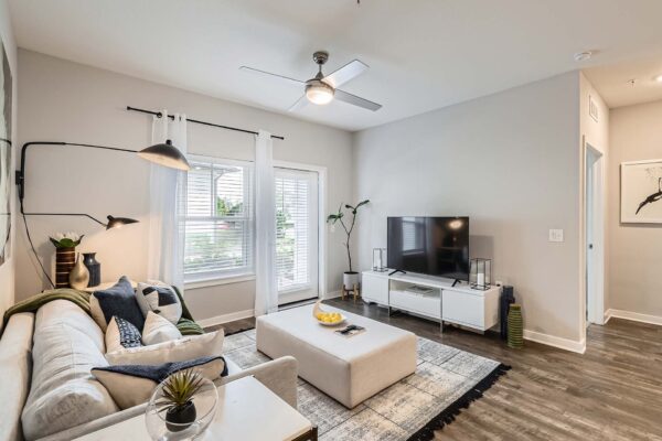 The Avery apartment living room with wood style floor, plush seating, and balcony door.
