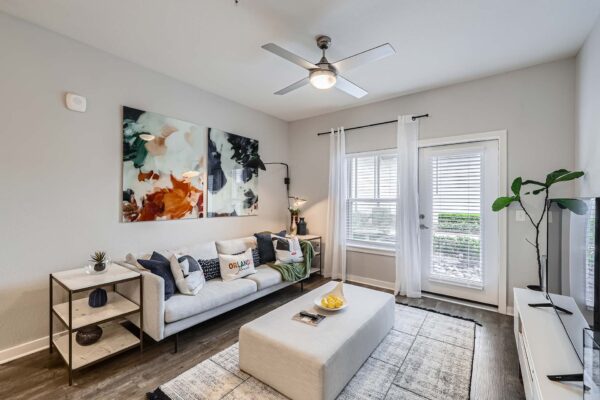 The Avery apartment living room with wood style floor, plush seating, wall art, and balcony door.