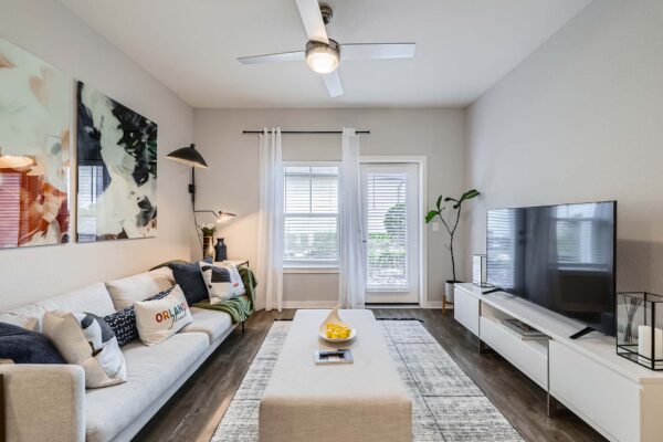 The Avery apartment living room with plush seating, wood style floor, and balcony door.