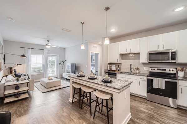 The Avery apartment kitchen with wood style floor, white cabinets, stone counters, and stainless steel appliances.