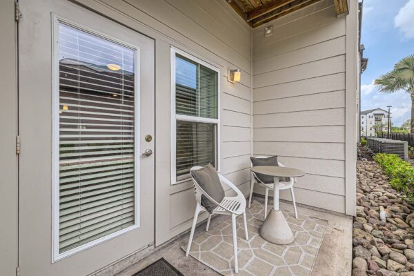 The Avery apartment balcony with outdoor seating and door to apartment.