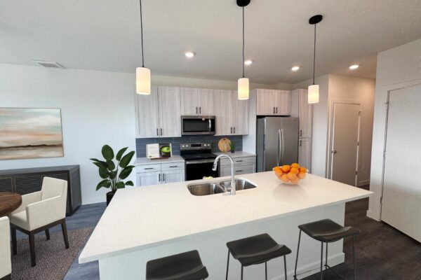29x apartment kitchen with wood style floor, breakfast bar with stools, pendant lights, and stainless steel appliances.
