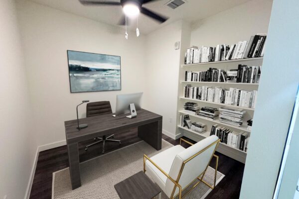 29x apartment office with ceiling fan, wood desk with computer, bookshelves, and framed artwork.