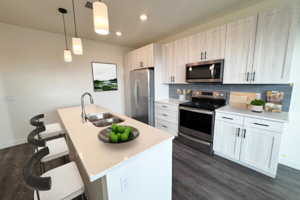 29x apartment kitchen with wood style floor, gray cabinets, stainless steel appliances, and breakfast bar with stools.