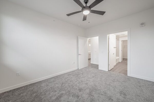 29x apartment bedroom with plush carpet and ceiling fan.