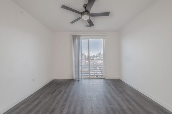 29x apartment bedroom with wood style floor, ceiling fan, and juliet balcony door.