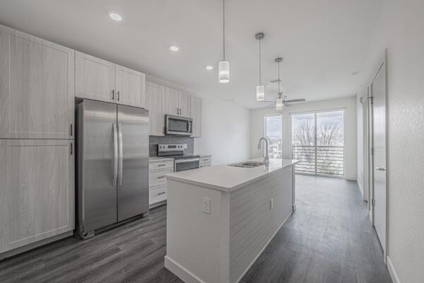 29x apartment kitchen with wood style floor, gray cabinets, light counters, pendant lights, and stainless steel appliances.
