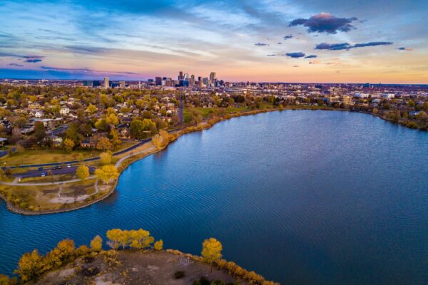 Aerial view of Denver, Colorado at sunset with large lake and distant skyline.