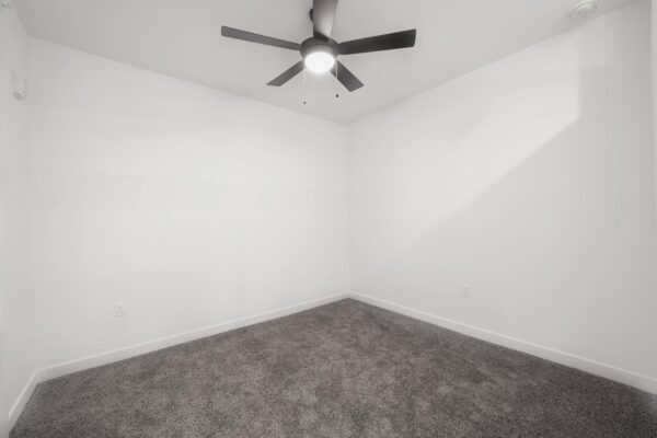 29x apartment bedroom with plush carpet and ceiling fan.