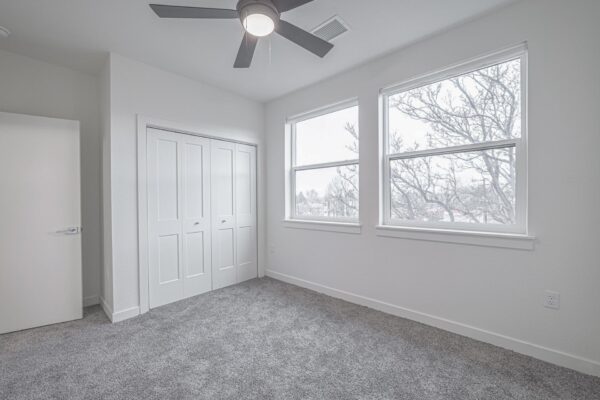 29x apartment bedroom with plush carpet, large windows, ceiling fan, and large closet.