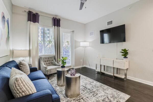 500 Ocean apartment living room with wood style floor, plush seating, wall mounted TV, and balcony door.