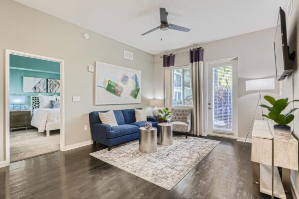 500 Ocean apartment living room with wood style floor, plush seating, wall mounted TV, and balcony door.