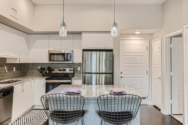 500 Ocean apartment kitchen with wood style floor, white cabinets, stone counters, and stainless steel appliances.