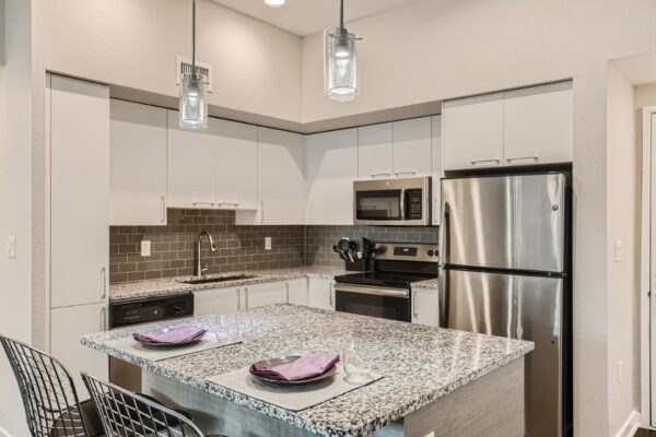 500 Ocean apartment kitchen with wood style floor, white cabinets, stone counters, and stainless steel appliances.