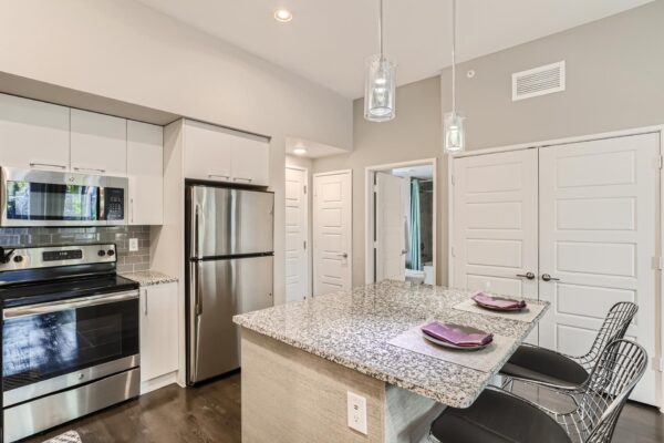500 Ocean apartment kitchen with wood style floor, white cabinets, stone counters, and stainless steel appliances.