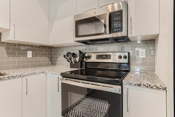 500 Ocean apartment kitchen with white cabinets, stone counters, and stainless steel appliances.