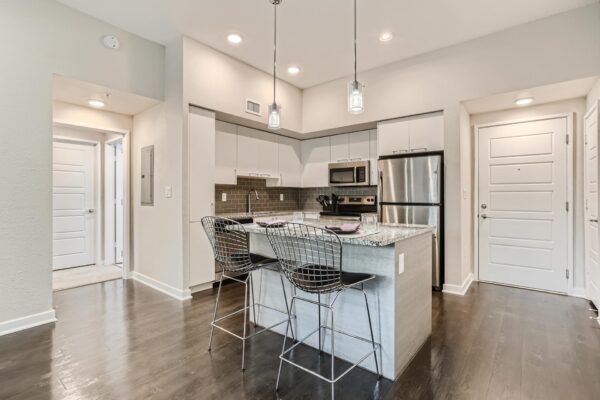 500 Ocean apartment kitchen with wood style floor, white cabinets, stone counters, and stainless steel appliances.