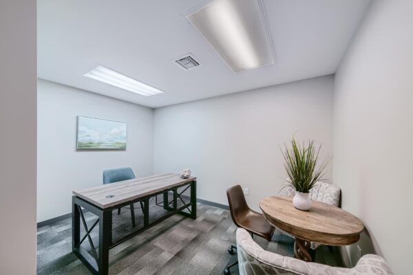 500 Ocean apartments office with desk, table with chairs, and wall art.