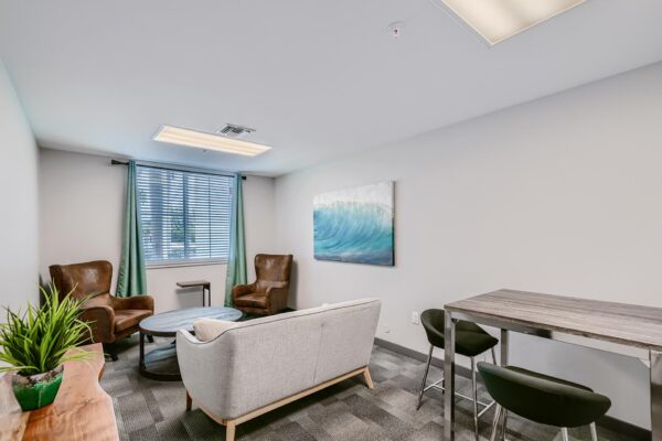 500 Ocean apartments office with plush seating, desk, large window, and wall art.