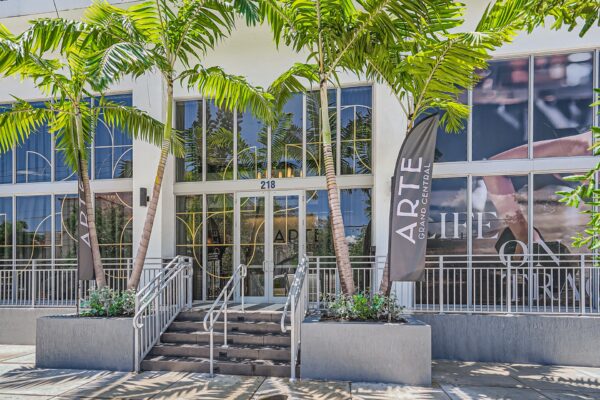 Arte Grand Central apartments leasing center entrance with large glass doors and palm trees.
