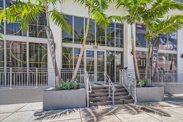 Arte Grand Central apartments leasing center entrance with large glass doors and palm trees.