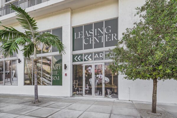 Arte Grand Central apartments leasing center entrance with large glass doors and palm trees.