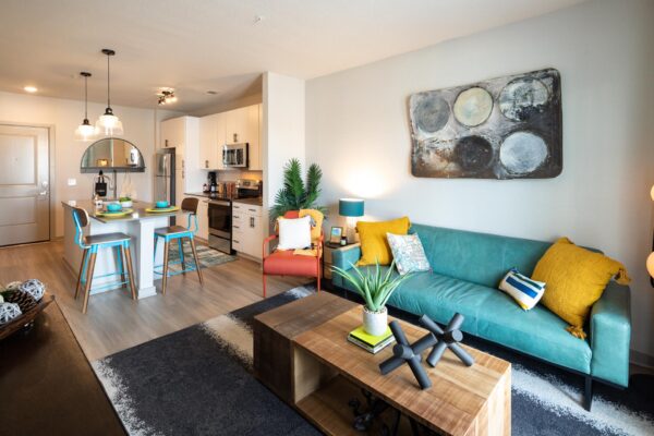 Arte St. Pete apartments kitchen and living room with stainless steel appliances, backsplash, wood-style floors.