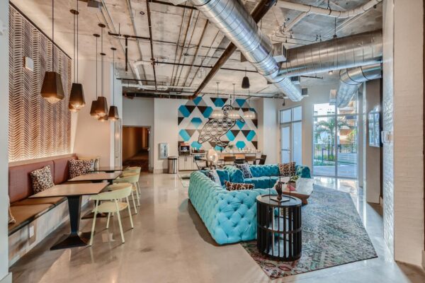 Arte St. Pete apartments community lounge with tv, sofas, tables, and chairs next to a coffee bar.