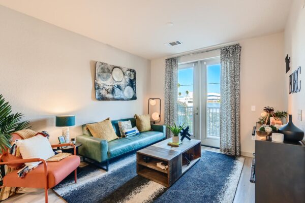 Arte St. Pete apartments living room with wood-style floors and door to balcony.