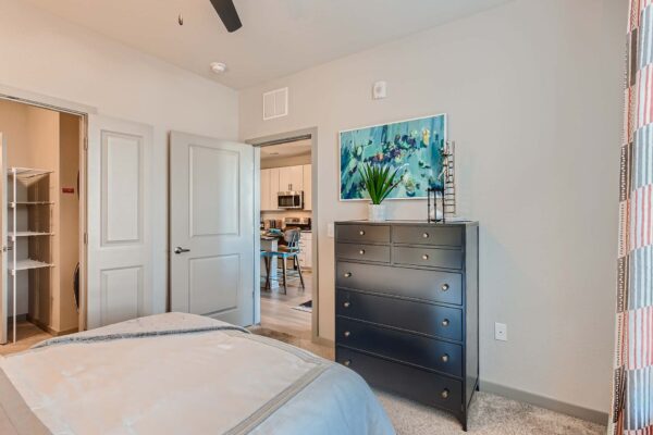 Arte St. Pete apartment bedroom with carpet, plush bed, dresser, and artwork.