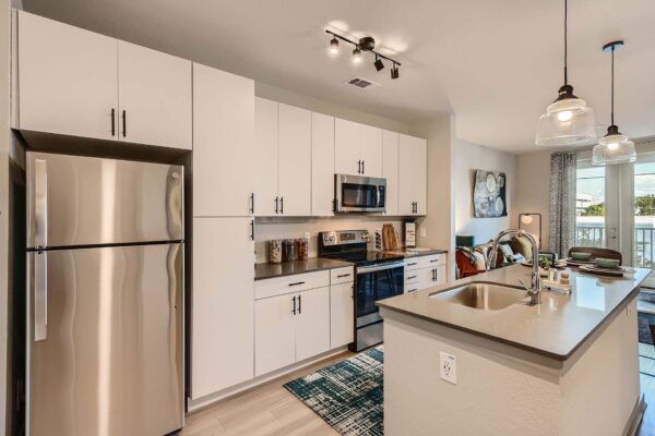 Arte St. Pete apartment kitchen with white cabinets, gray counters, and stainless steel appliances.