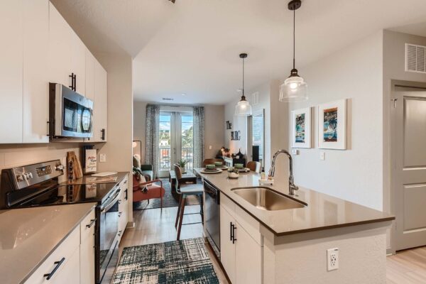 Arte St. Pete apartment kitchen with white cabinets, gray counters, and stainless steel appliances.