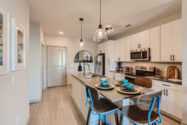 Arte St. Pete apartment kitchen with white cabinets, gray counters, and stainless steel appliances.