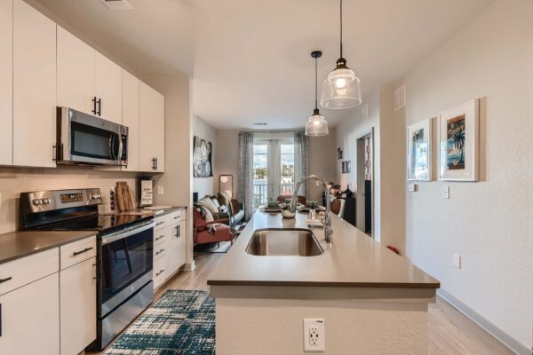 Arte St. Pete apartment kitchen with white cabinets, gray counters, and stainless steel appliances.