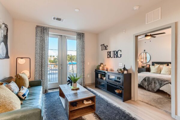 Arte St. Pete apartment living room with wood style floor, plush seating, and balcony door.