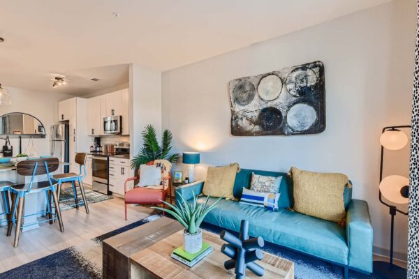 Arte St. Pete apartment living room with plush seating, large artwork, and modern kitchen.