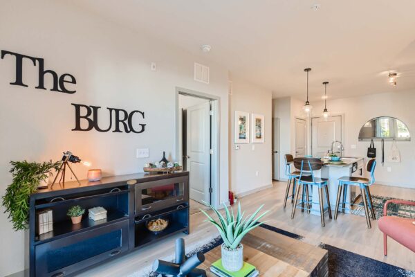 Arte St. Pete apartment living room with wood style floor, plush seating, and eclectic decor.