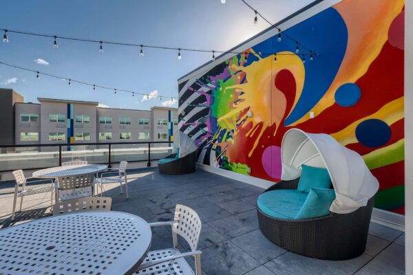 Arte St. Pete apartments rooftop lounge with tables, daybeds, and colorful mural.