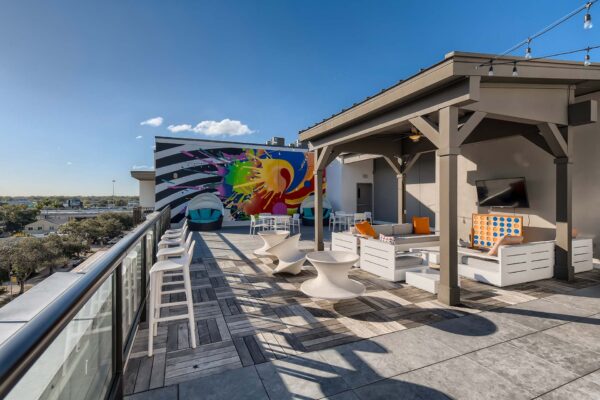 Arte St. Pete apartments rooftop deck with plush seating, TV, and colorful mural.